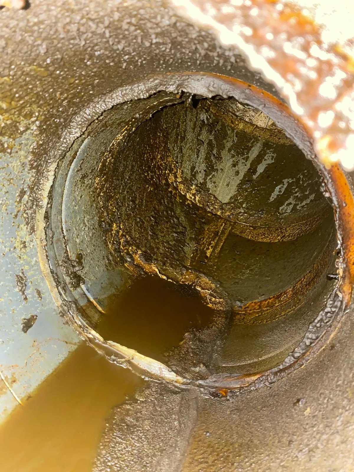 Spiral duct bend before cleaning, with heavy grease build-up